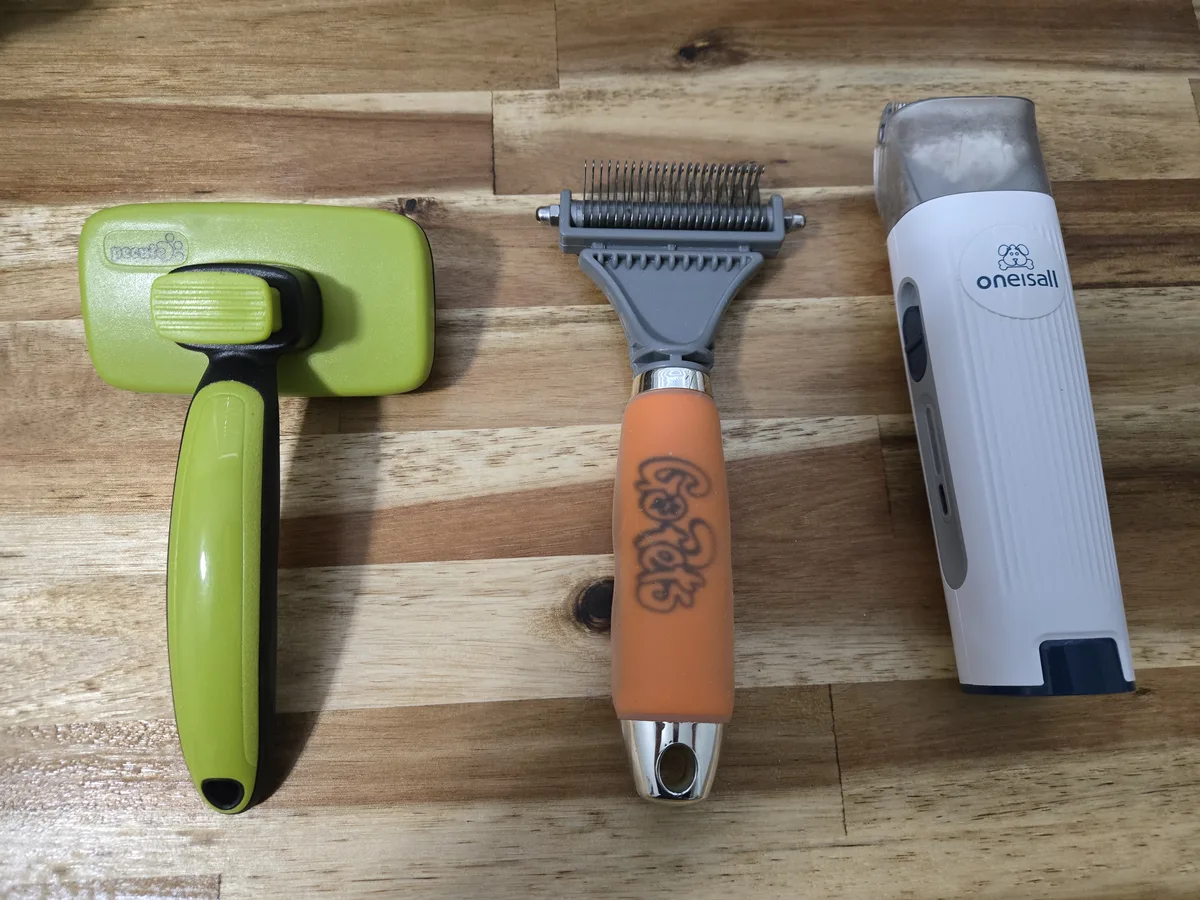 Our three most-used grooming tools: Pecute slicker brush, GoPets dematting comb, and the oneisall clipper/vacuum