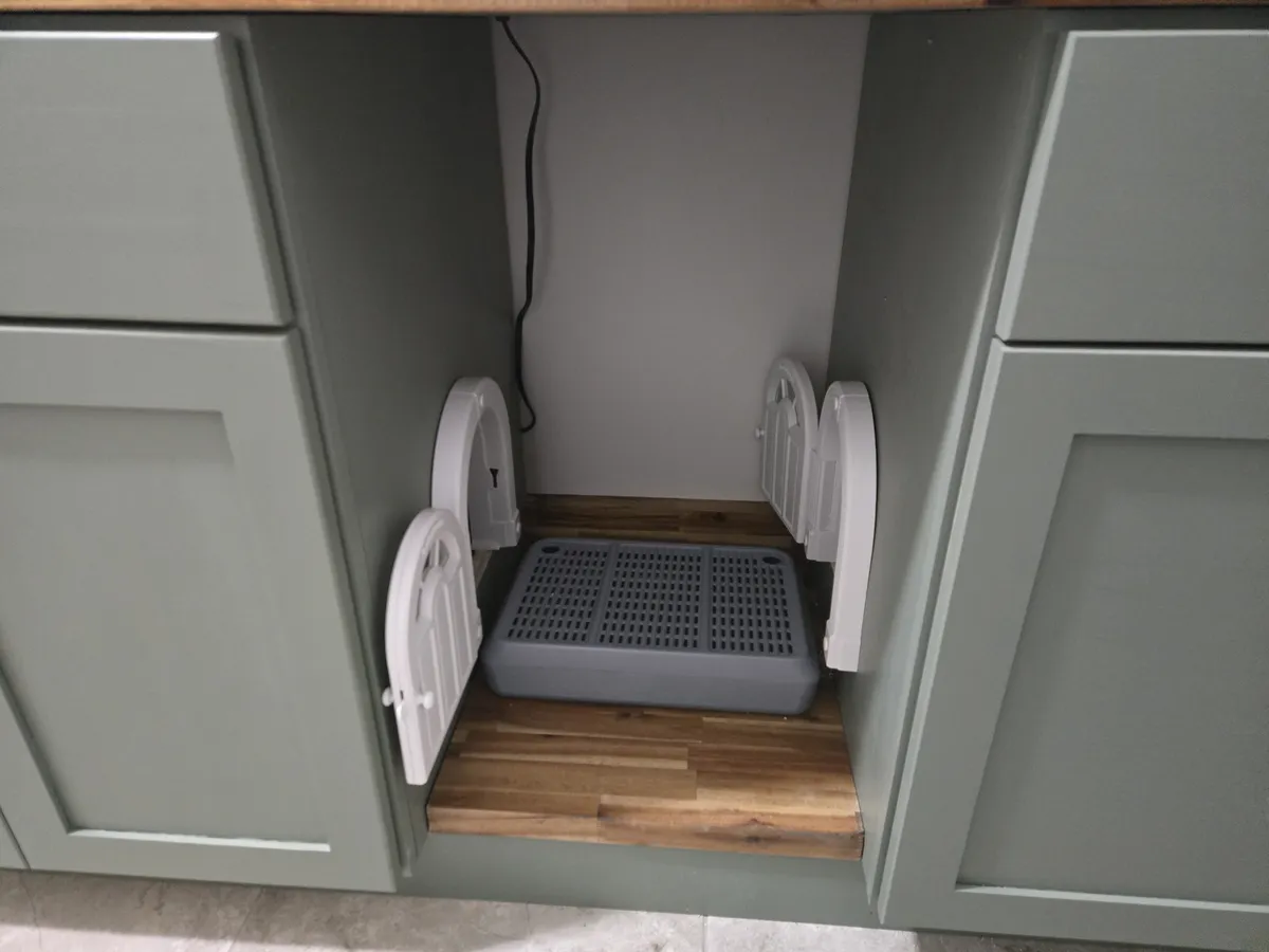 Center cabinet open showing the litter mat and two Purrfect Portal XL cat doors facing each other on the side panels