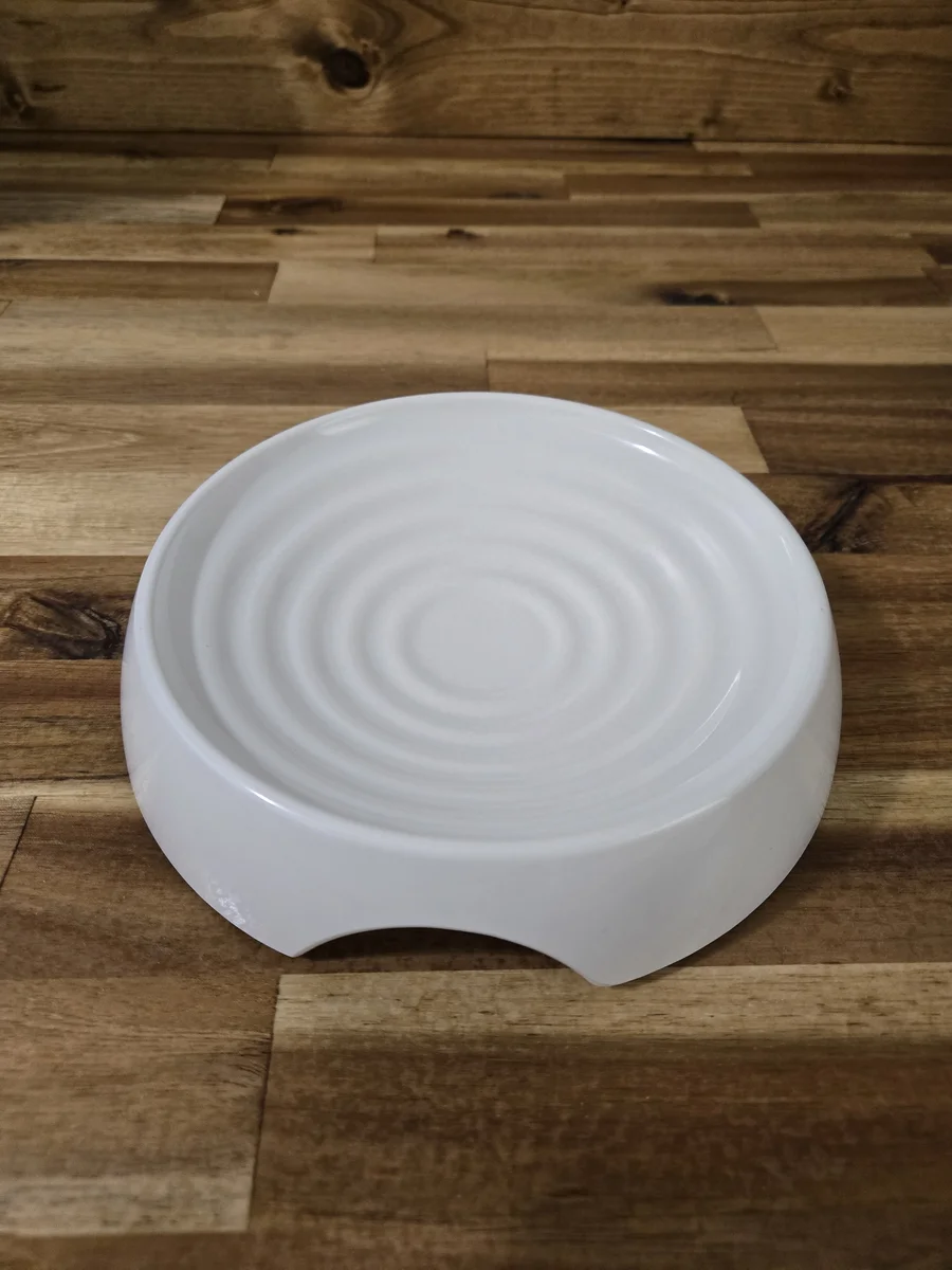 The ridged ceramic lick plate — those concentric rings keep the puree in place instead of sliding everywhere