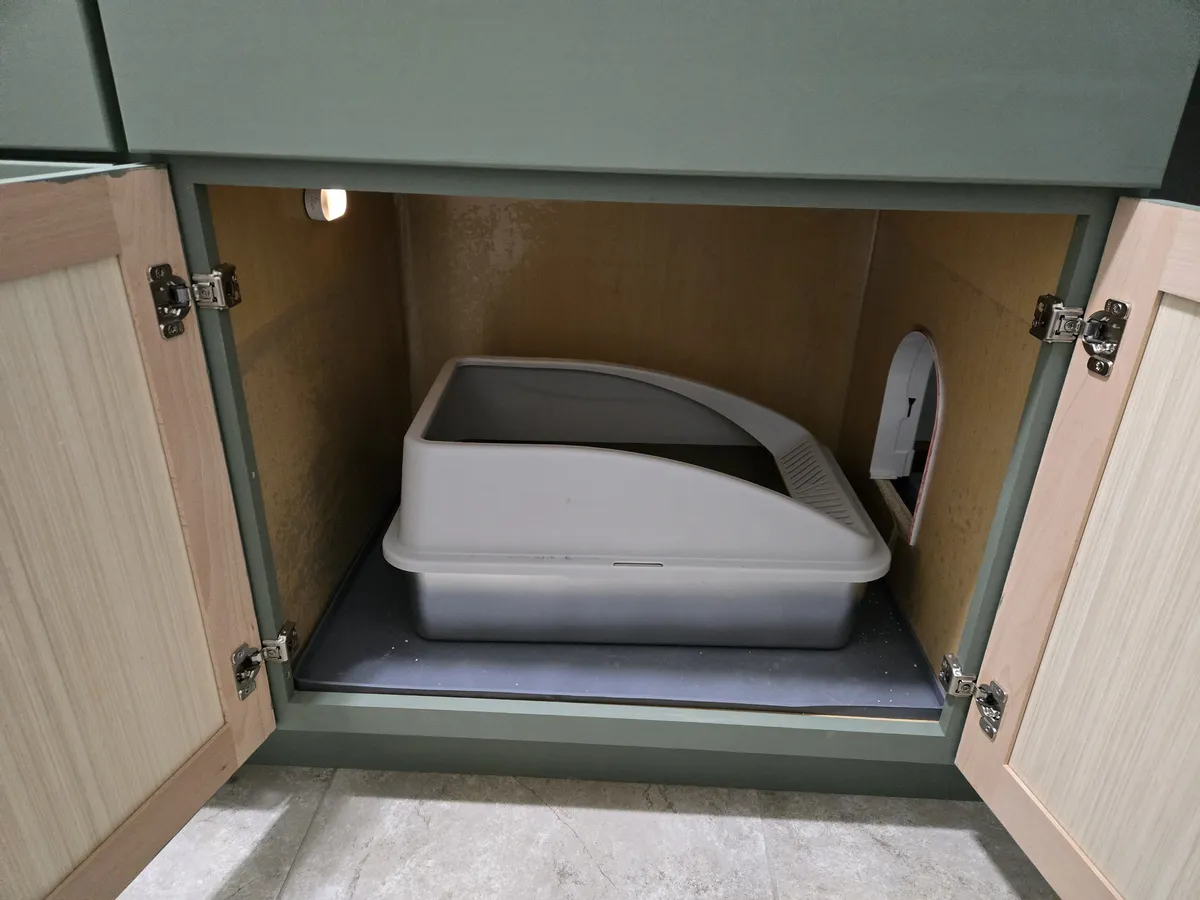 The AIPERRO enclosed stainless steel litter box inside the second cabinet station, with the cat door visible on the right side panel