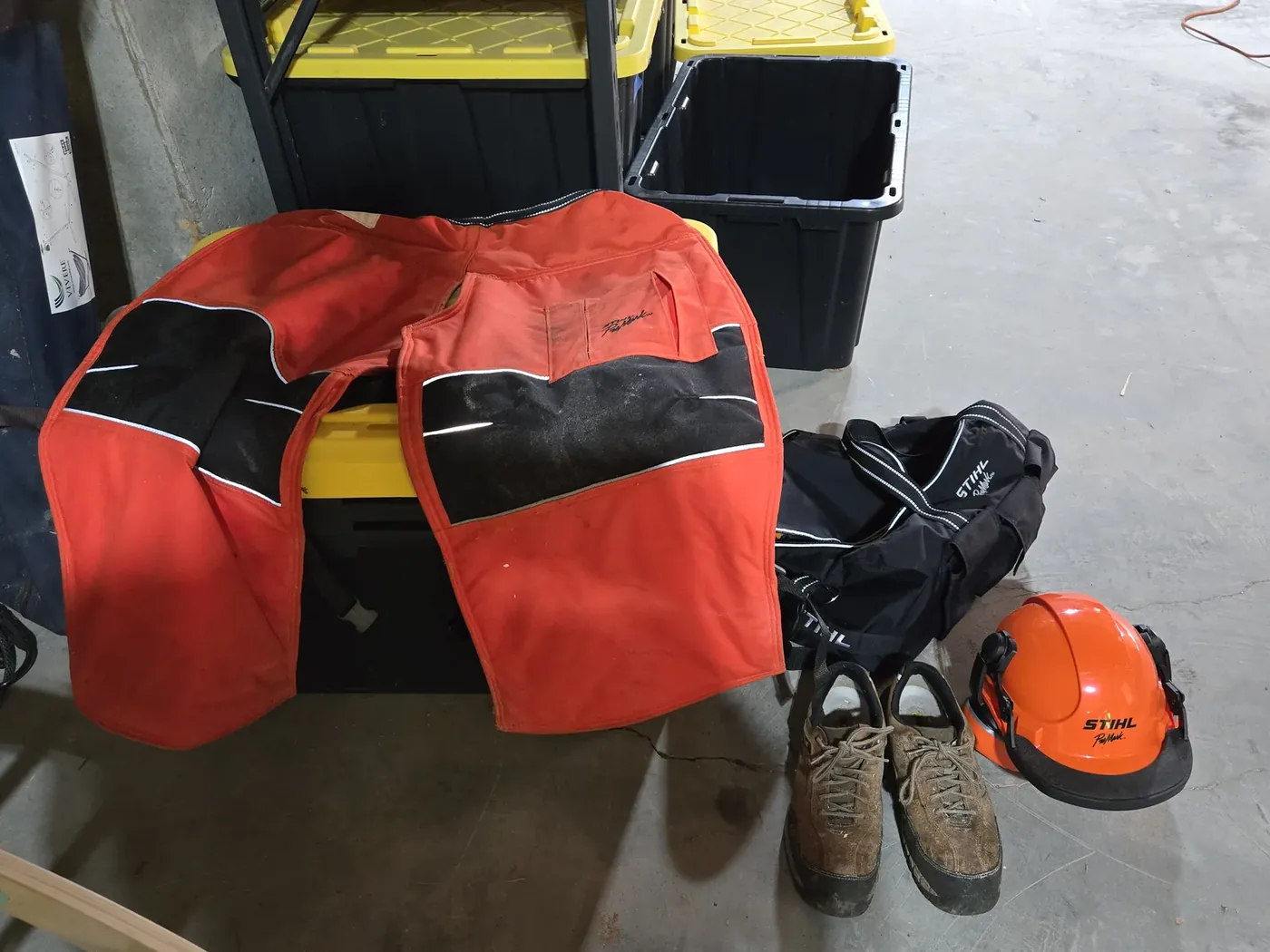 Stihl chaps, carry bag, boots, and helmet laid out on the garage floor