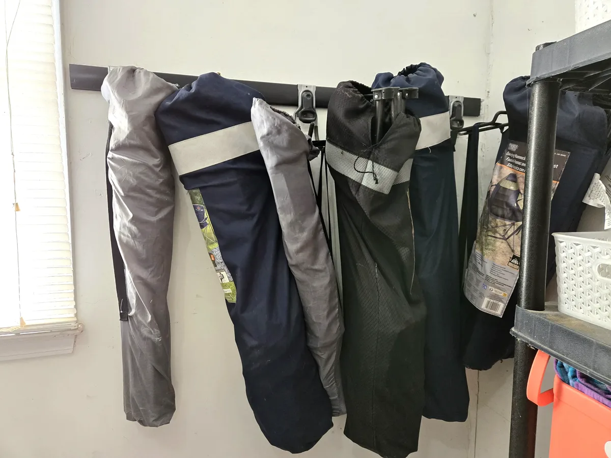 Camping chairs and canopy bags hanging on a FastTrack rail in the corner