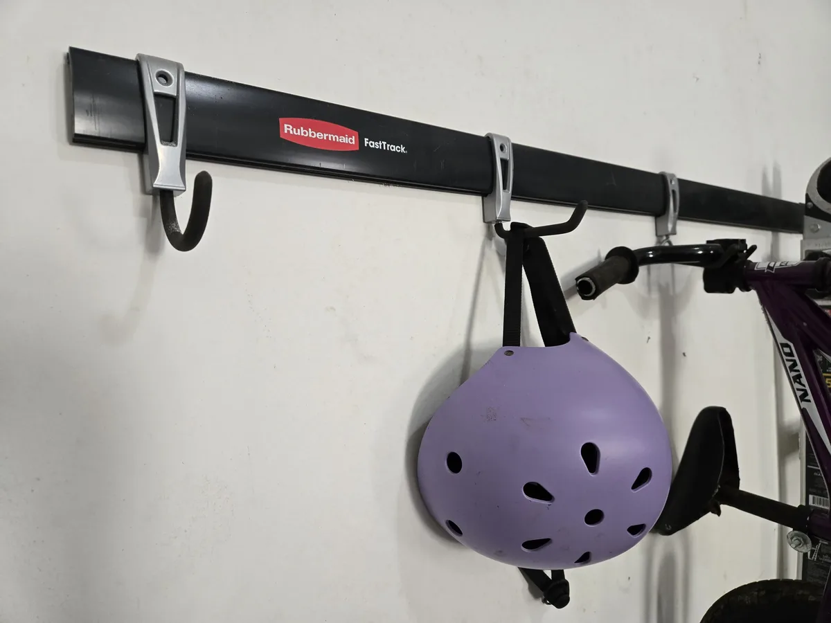 Close-up of the Rubbermaid FastTrack rail with utility hooks holding a helmet and bike