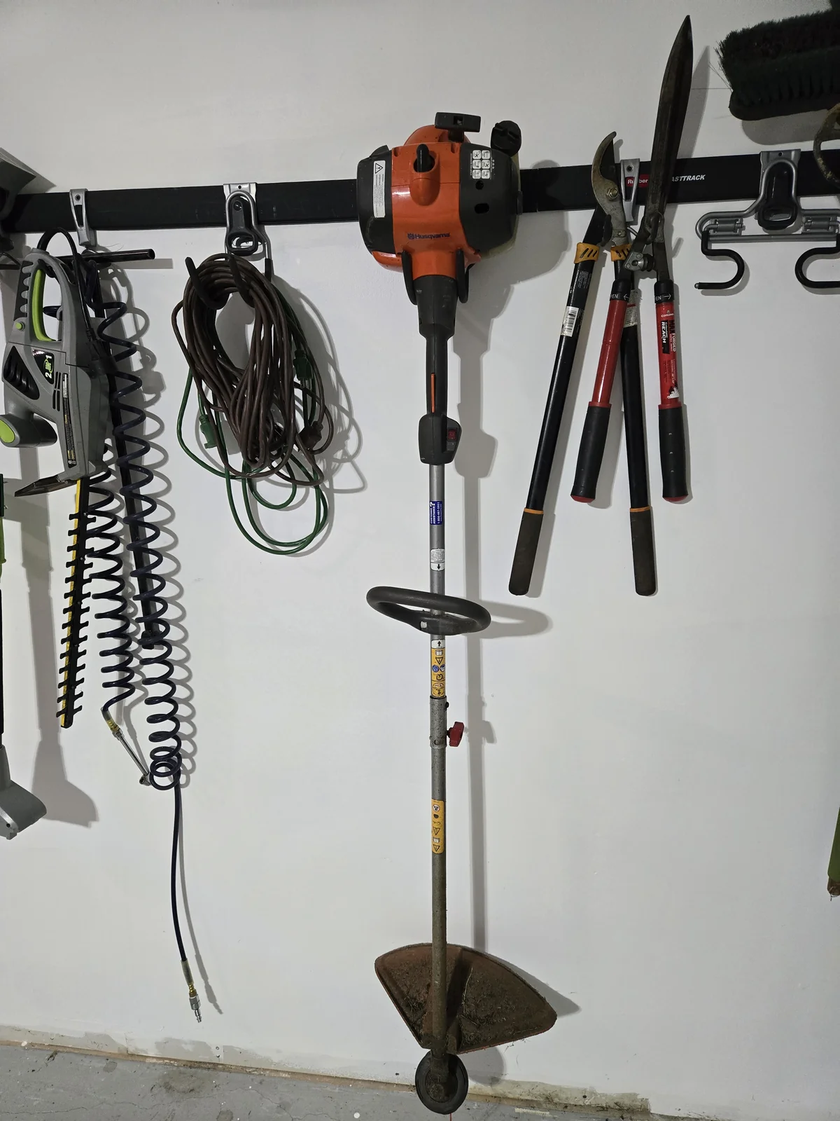 Loppers, trimmer, cords, and the hedge trimmer on the FastTrack rail — level, dry, and findable in spring