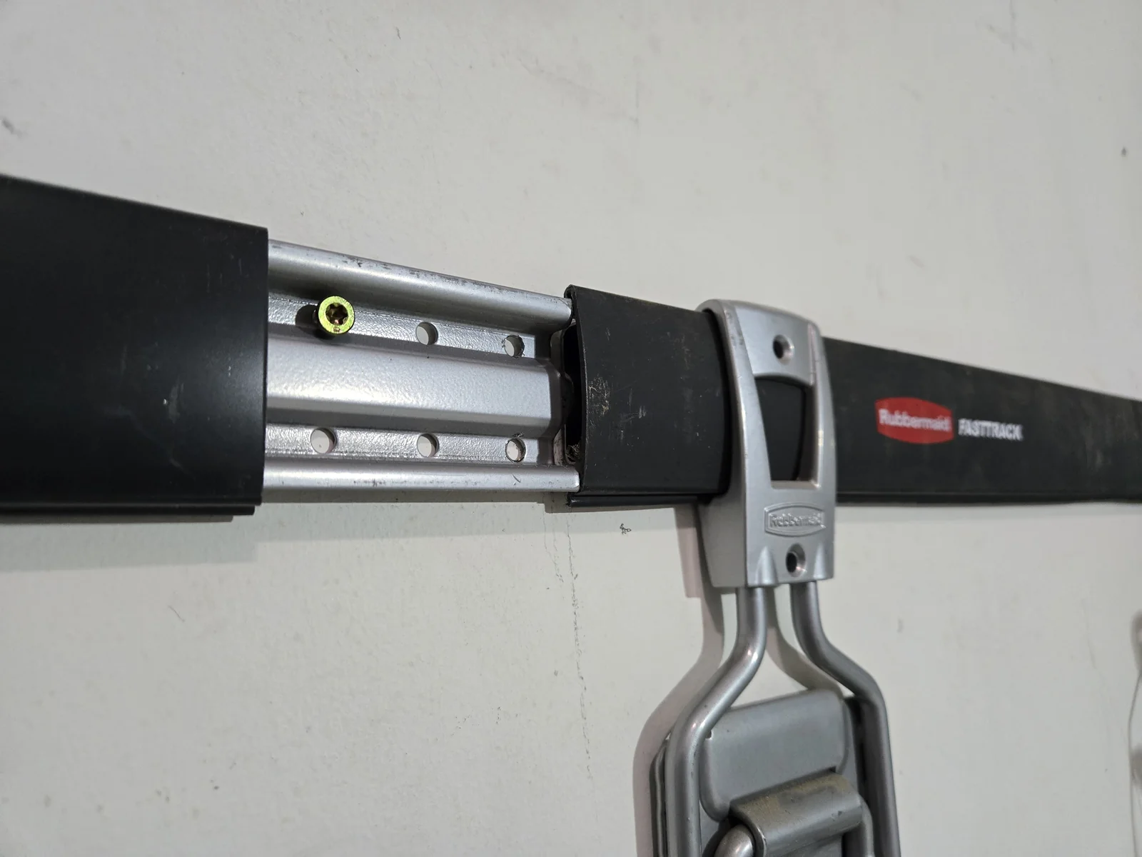 Construction screws driven through Rubbermaid FastTrack rail mounting holes into wall studs